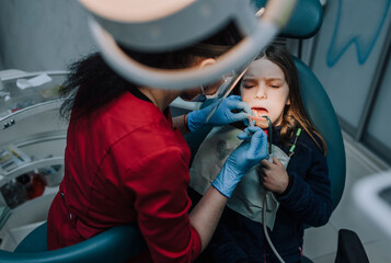 Dentist, professional doctor woman in rubber gloves with tools diagnoses, treats teeth from caries...