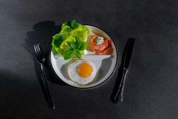 top view of healthy ketogenic breakfast with fried egg, green salad and smoked salmon