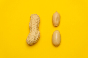 Whole peanut in the shell and peeled on a yellow background. Protein and healthy dried fruit. Cool minimal flat lay, copy space 
