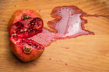 A juicy Pomegranate cut in half on a wooden cutting board and yellow background.