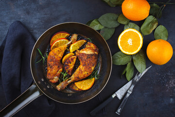 Traditional barbecue chicken drumsticks with orange slices served with herbs as top view on a...