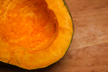 An organic pumpkin cut in half on a wooden cutting board