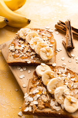 Homemade toast with banana, honey and oatmeal closeup on a yellow background