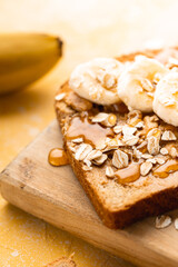 Homemade toast with banana, honey and oatmeal closeup on a yellow background