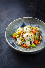 Traditional Peruvian gourmet ceviche sea bass filet piece with sweet potatoes and cancha marinated and served in lime sauce as close-up in a Nordic design bowl