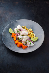 Traditional Peruvian gourmet ceviche sea bass filet piece with sweet potatoes and cancha marinated and served in lime sauce as close-up in a modern design plate
