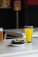 A plate of olives next to an orange soda. Spanish tapas.