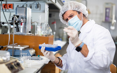Fototapeta premium Portrait of confident male scientist working in medical science laboratory, provide testing services and looking at test tube