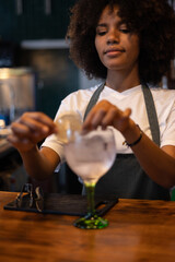 Portrait of young African female bartender preparing a drink at the bar of a restaurant.