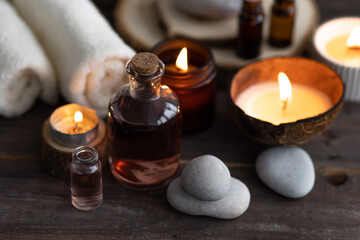 Concept of natural essential organic oils, Bali spa, beauty treatment, relax time. Atmosphere of relaxation, pleasure. Candles, towels, dark wooden background. Alternative oriental medicine