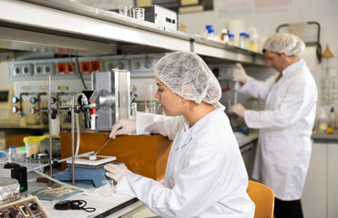 Female laboratory assistant weighs tablets on precision scales in a biochemical laboratory