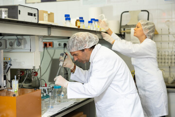 Fototapeta na wymiar Concentrated man and woman chemists checking reagent in test tube during scientific research in modern laboratory