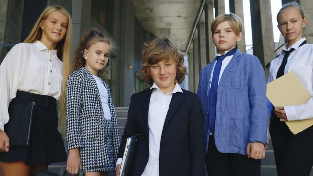Close up portrait of the preteen business kids looking at the camera. Pupils after school. Kids business team. Young employees standing outside together near the office centre