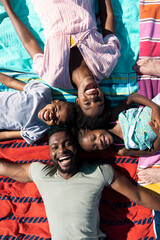 Overhead view of cheerful african american parents and children lying down on towels at beach