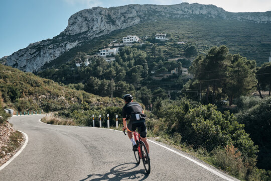 A professional cyclist's epic mountain ride.Male cyclist riding in the mountains.Man cyclist wearing cycling kit and helmet.Beautiful motivation image of an athlete.Descending the mountain.Xàbia,Spain