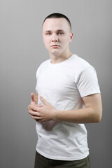 Studio portrait of handsome confident young man in casual white t shirts with mock up crossed his hands and looking at camera isolated on grey background.
