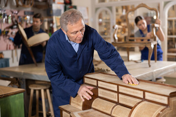 Fototapeta na wymiar Senior male furniture workshop worker designing vintage chest of drawers