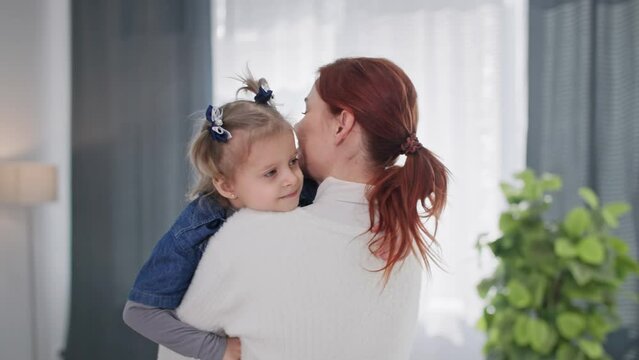 childhood, portrait of an adorable little girl with ponytails in the arms of a female parent in a cozy apartment