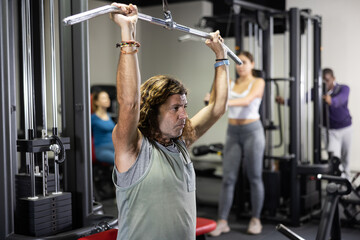 Caucasian man doing exercises on lat pull down machine in gym