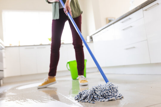 Low section of caucasian young woman cleaning floor with wet mop at home, copy space