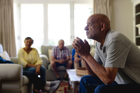 Group of emotional, diverse senior friends in living room, talking during group therapy session