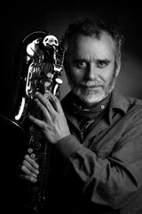 shot of a male musician, saxophonist, holding a saxophone alto jazz musical instrument and...