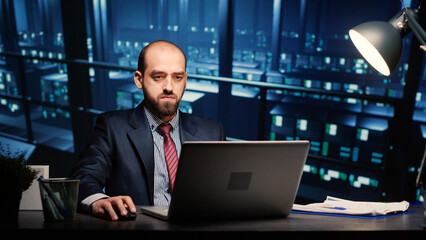 Server technician specialist working on laptop running networking diagnostics on cyber security racks in modern data center. IT engineer inspecting big data connection, technology concept.