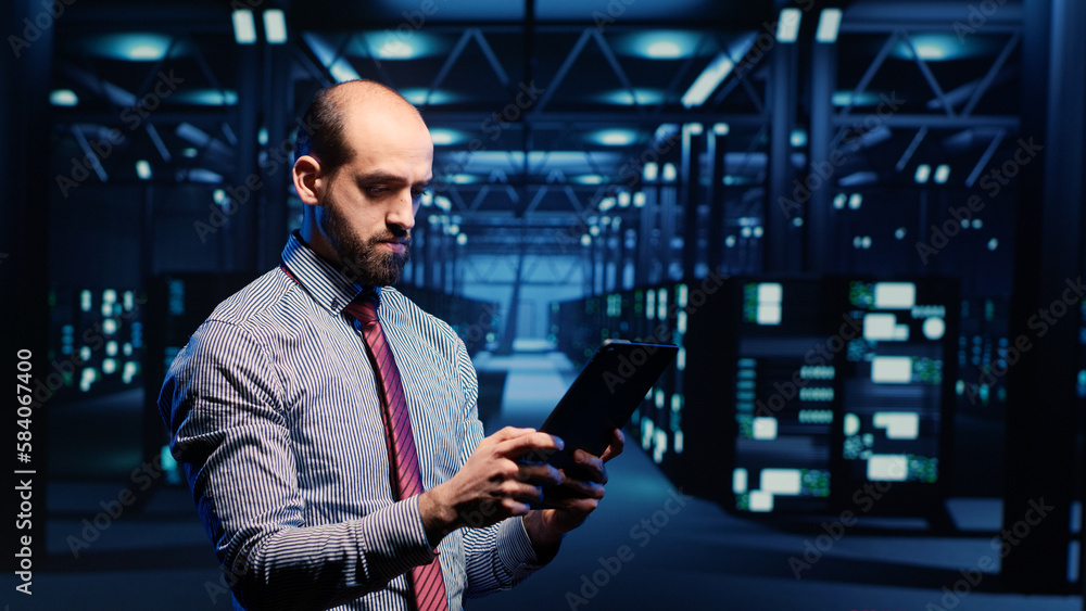 Poster system administrator activating hardware in data center with tablet, analyzing modern servers in ser