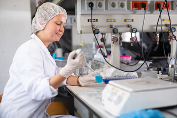 Focused young adult female scientist working in medical science laboratory, doing research