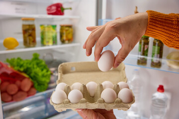 man hands take white chicken eggs from the fridge