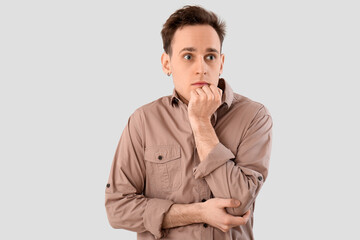Scared young man on light background