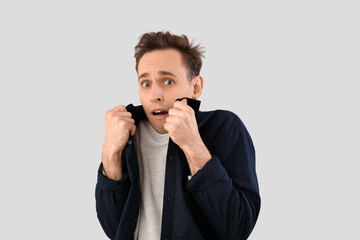 Scared young man on light background