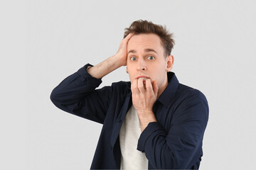 Scared young man on light background