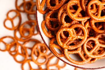Bowl of tasty salted pretzels on light background, closeup