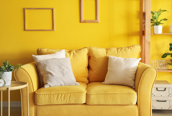 Interior of living room with yellow sofa and frames