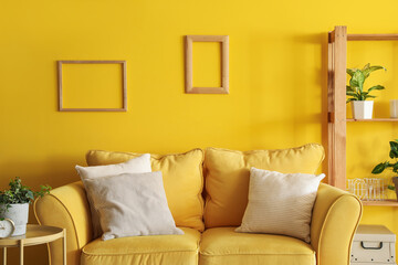 Interior of living room with yellow sofa and frames