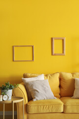 Interior of living room with yellow sofa and frames