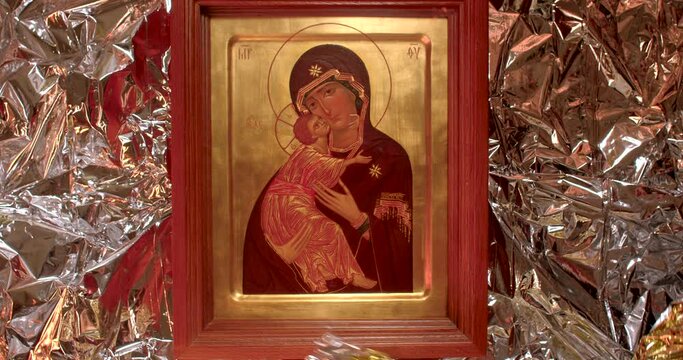 Icon Blessed Mother Mary and Jesus child of God as a gift in golden package. Hands in white gloves carefully unpack, close up.
