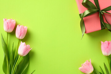 Flat lay composition with tulips and gift box on green background. Happy Mother's Day concept.