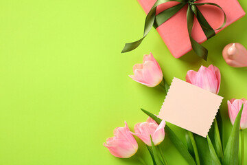 Happy Mother Day greeting card template. Flat lay composition with tulips, gift box, greeting card mockup on green background
