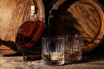 Oak barrels with bottle and glasses of cold whiskey on table