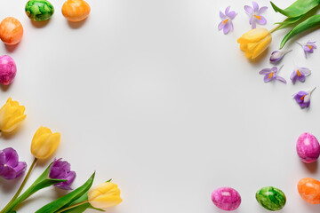 Composition with painted Easter eggs and spring flowers on light background