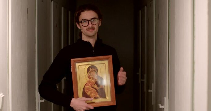 Young man found a rare icon is a sacred image used in religious devotion and poses for TV, showing off his find. Narrative scenes from the Bible or the lives of saints. 