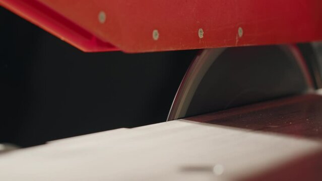 Close-up of carpenter cutting a wooden plank, circular saw on wooden factory, furniture production, handmade craft table.