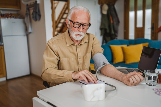 Man senior caucasian male use device to measure blood pressure at home