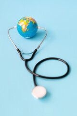 World ball and stethoscope isolated on light blue background. Worldwide health concept and care of the planet.