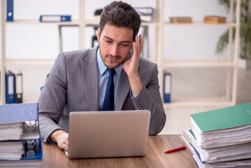 Young male employee and too much work in the office