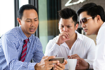 Successful Businessmen sitting in cafe and discussing business project. Business people meeting, analyzing and discussing with computer tablet. Digital life style.