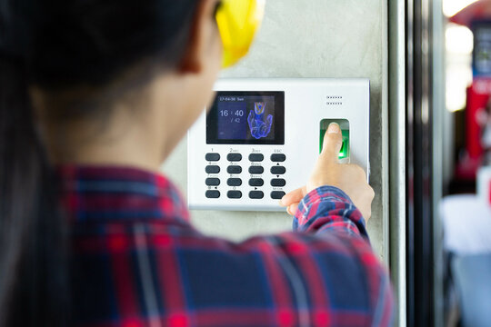 Woman foreman or Architect  scanning her fingerprint on the machine to record working time or access control. Fingerprint scanner for security system in digital technology concept.