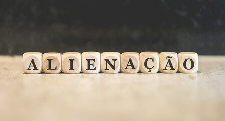 A palavra alienação em Português do Brasil escrita em dados de madeira.